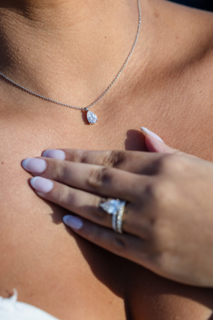 Close-up of bride AnnaLisa’s pear-shaped diamond pendant and engagement ring, capturing timeless bridal details during her wedding.
