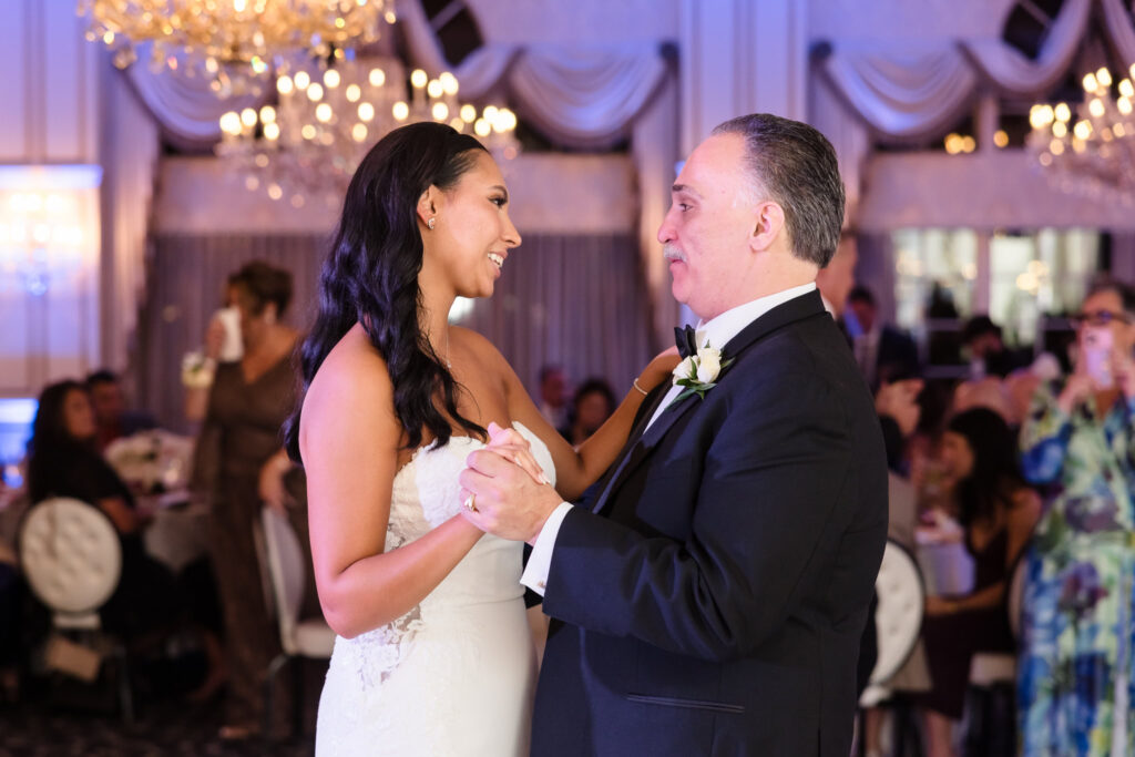 Bride AnnaLisa shares a touching father-daughter dance under sparkling chandeliers at Giorgio’s Baiting Hollow, surrounded by emotional family and friends