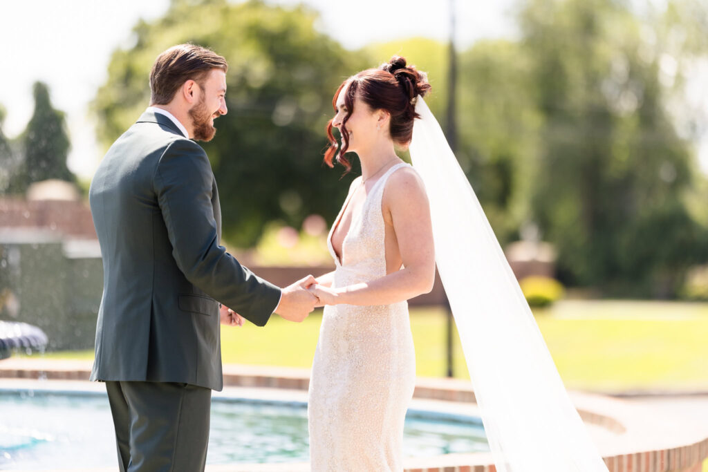 Bride and groom share an emotional first look near the fountain at Hiland Park Wedding Venue, bathed in natural sunlight on their wedding day in Upstate NY.