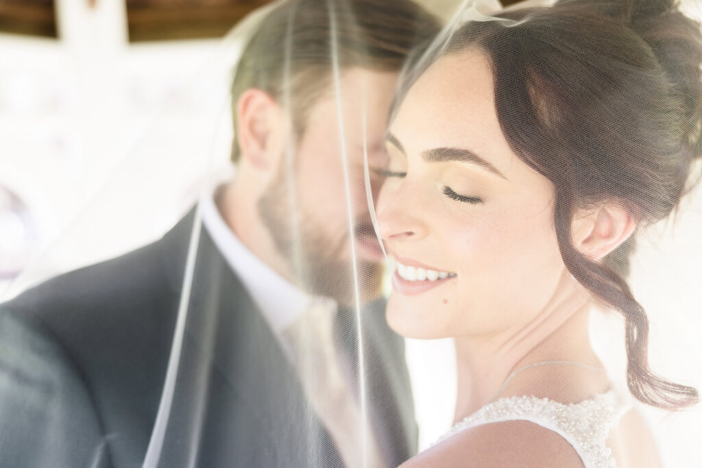 Close-up of bride and groom sharing a quiet moment under her wedding veil at Hiland Park Wedding Venue, capturing soft intimacy and romantic connection.