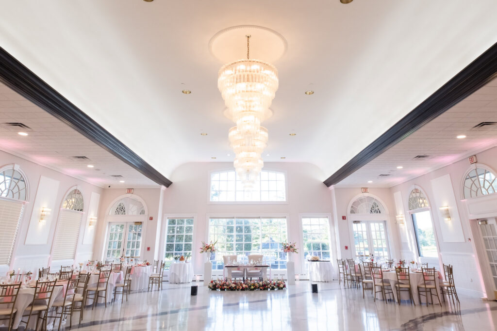 Elegant reception ballroom at Hiland Park Wedding Venue featuring crystal chandeliers, arched windows, and floral accents surrounding the sweetheart table.