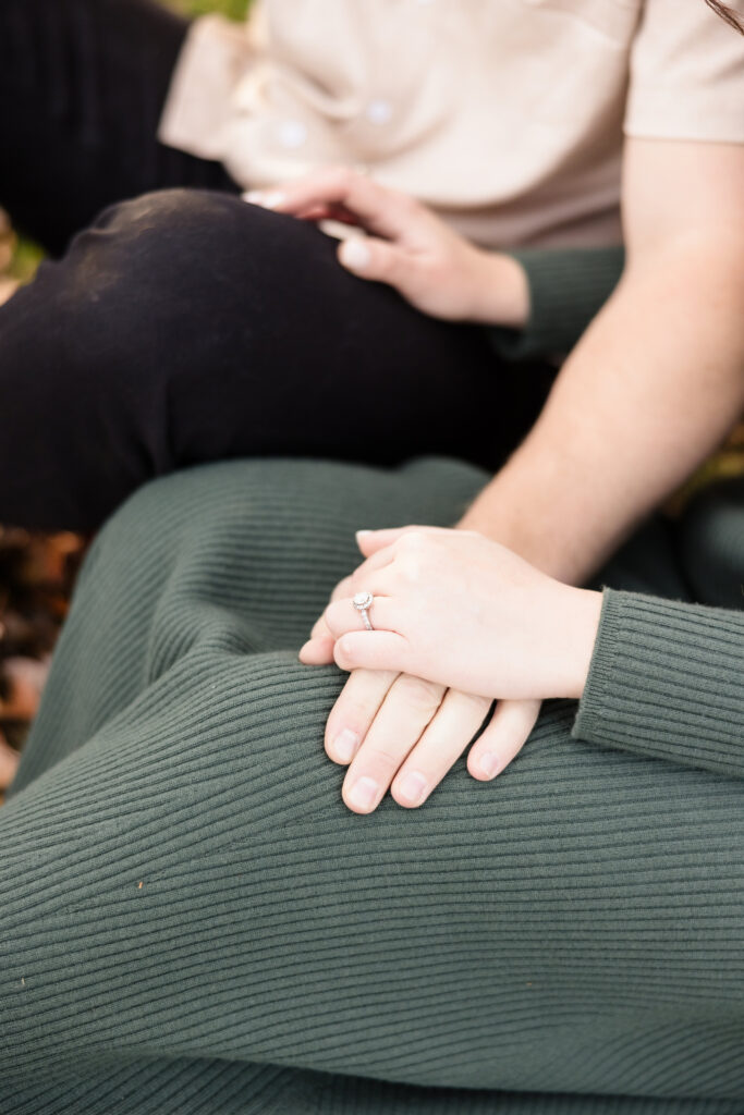 Close-up of hands resting gently with a diamond engagement ring on display, capturing quiet intimacy and emotional detail during a late fall session.