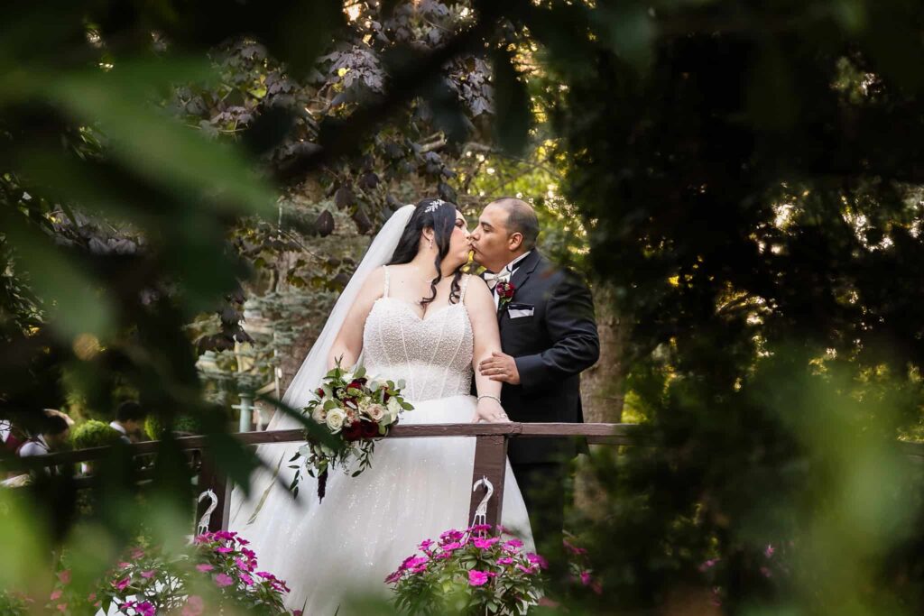 Elegant floral urns filled with white hydrangeas, blush roses, and deep red blooms line the garden ceremony aisle at Westbury Manor, creating a classic and romantic outdoor wedding setting.