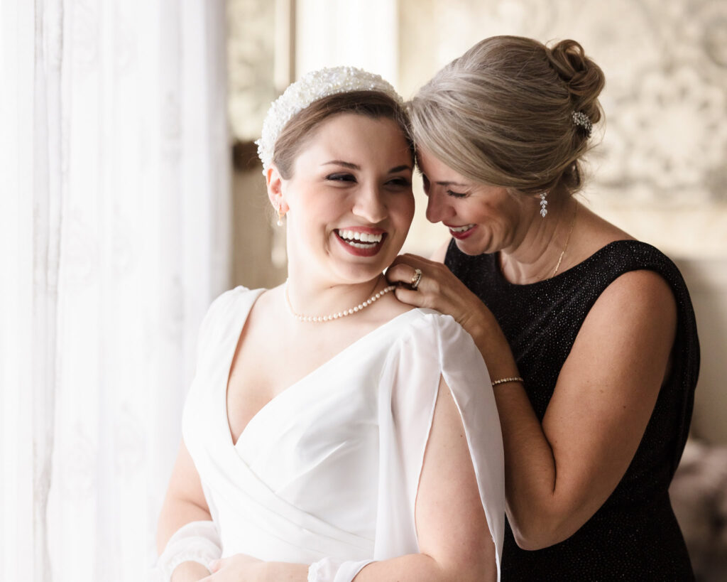 Bride sharing a joyful moment with her mother while getting ready in the bridal suite at Giorgio’s Baiting Hollow before her winter wedding ceremony.