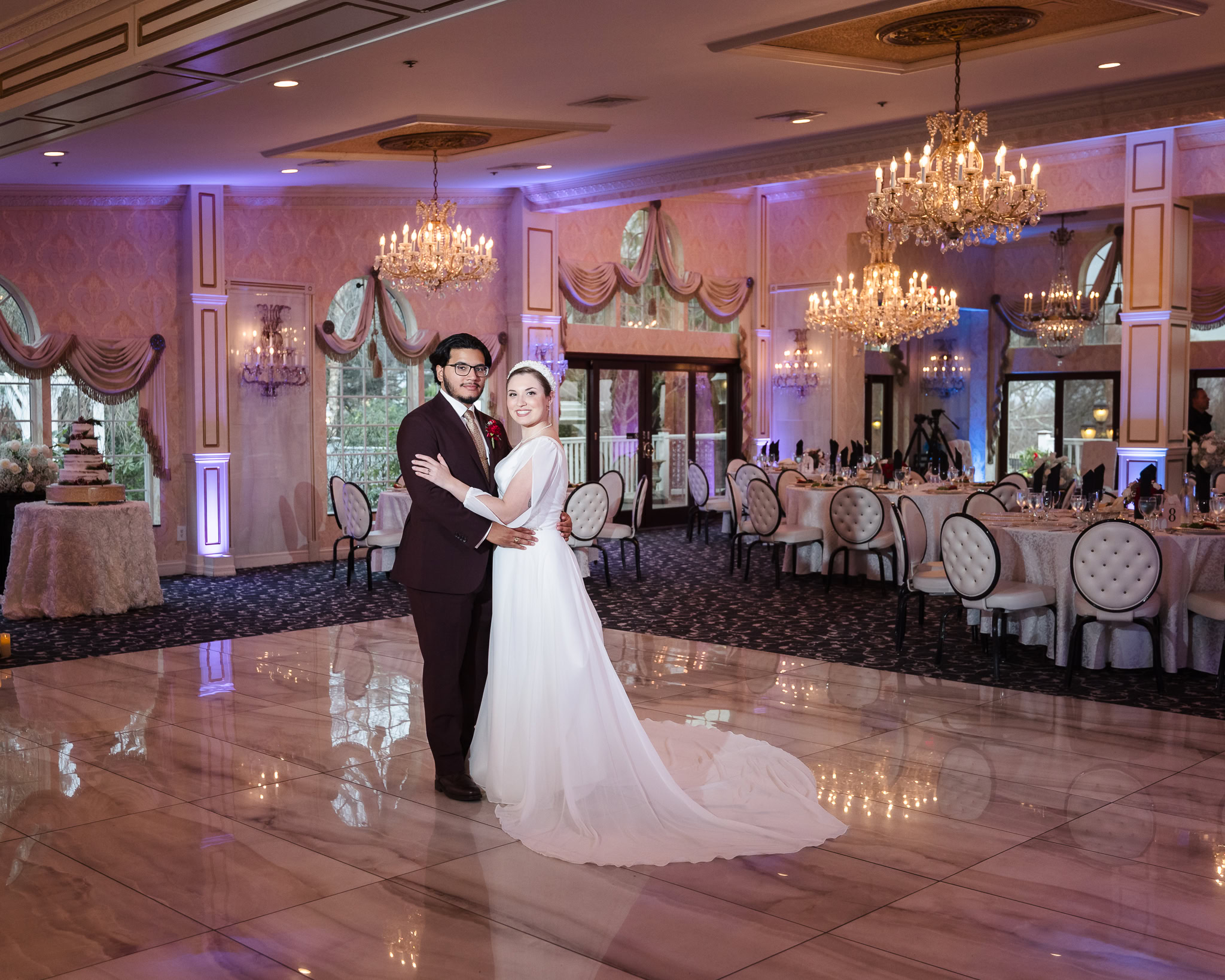 Bride and groom standing together on the dance floor of Giorgio’s Baiting Hollow ballroom, surrounded by elegant chandeliers and winter wedding reception decor.