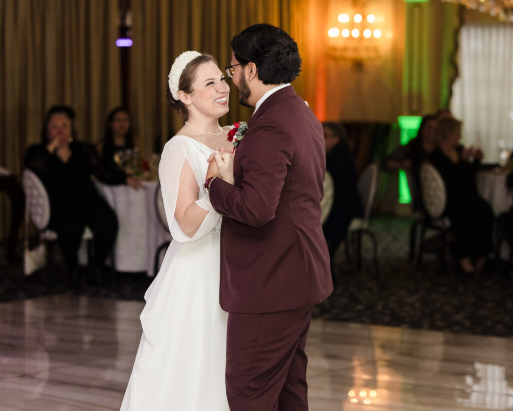Bride and groom sharing their first dance on the marble floor at Giorgio’s Baiting Hollow, smiling and surrounded by guests during their winter wedding reception.Here is the SEO-friendly alt text for Image 18: Alt Text: Silhouetted portrait of bride and groom in an intimate embrace with golden bokeh and warm backlighting during their winter wedding at Giorgio’s Baiting Hollow.