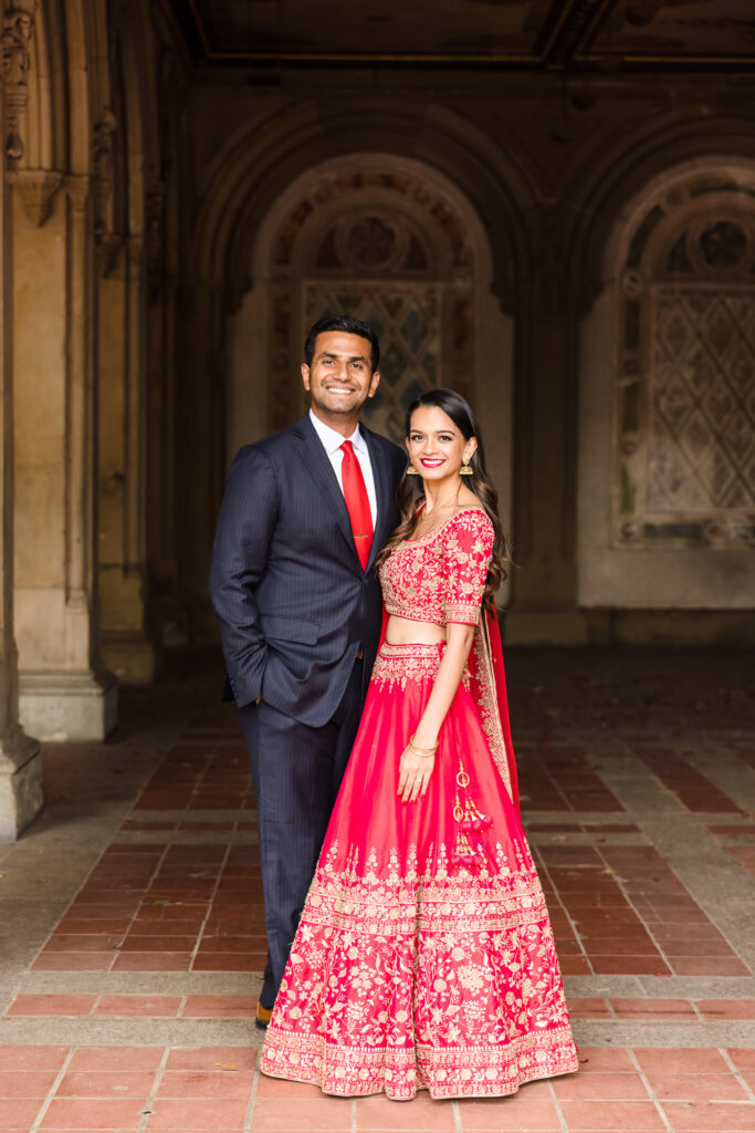 Engaged South Asian couple posing at Bethesda Terrace in Central Park, blending modern elegance with traditional Indian engagement attire.
