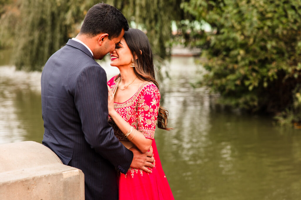 Romantic moment between a South Asian couple embracing by the lake during their Central Park engagement session with traditional attire.