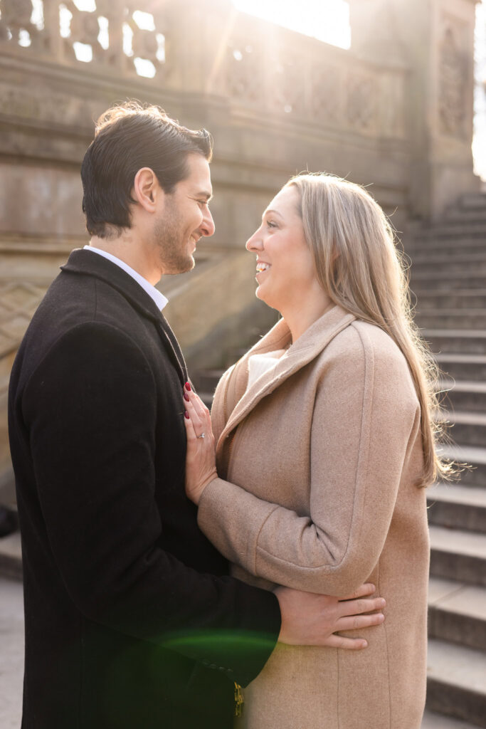 Couple shares a quiet moment in soft winter sunlight near the Bethesda Terrace steps during their Central Park engagement session.