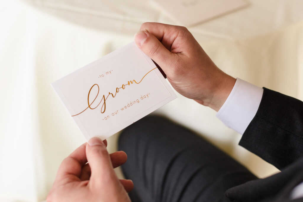 Groom holding a wedding day letter from his bride, a heartfelt moment captured before their wedding on Long Island’s scenic waterfront.