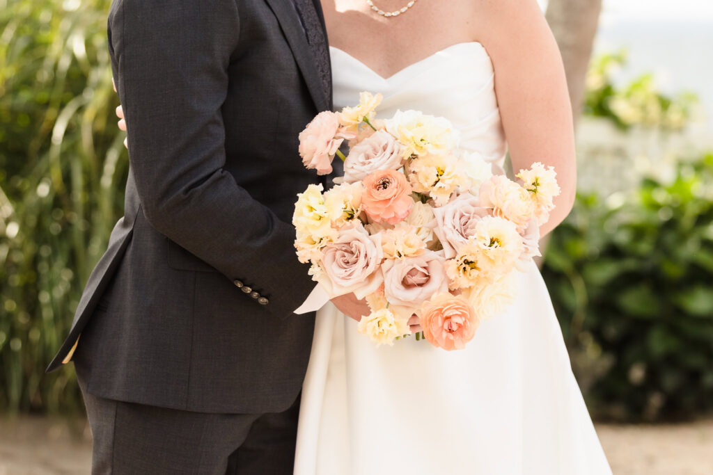 Close-up of the bride’s pastel bouquet featuring peach, blush, and cream florals, held during a beach wedding in September on Long Island’s waterfront.