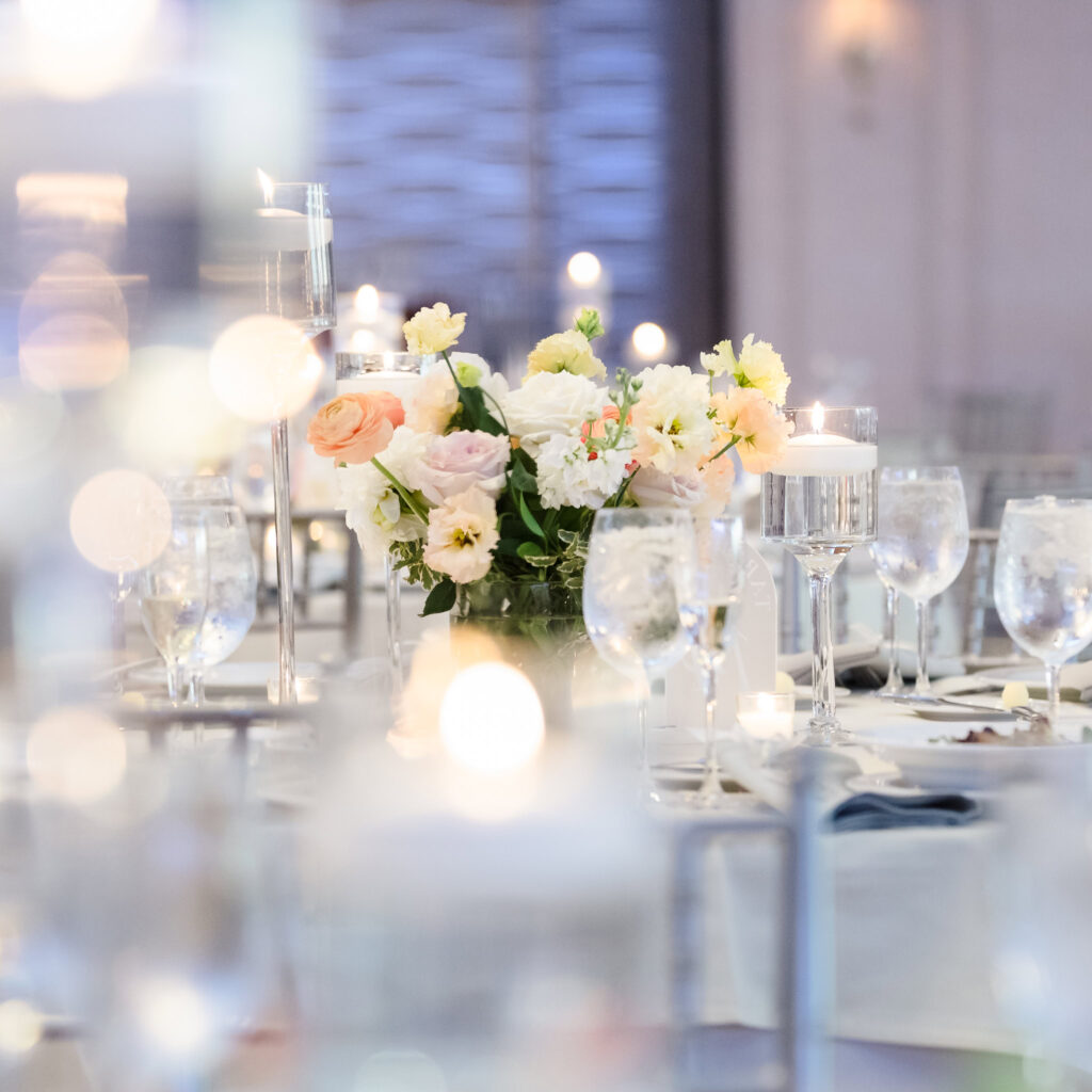Romantic reception table setting at a wedding, featuring pastel florals, floating candles, and soft lighting for an elegant Long Island waterfront celebration.