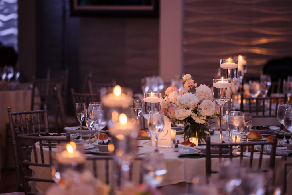 Candlelit reception table at a wedding, with soft pastel florals, floating candles, and elegant dinnerware setting the tone for a refined Long Island evening celebration.