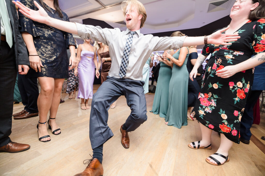 Wedding guest dances with full energy on the reception floor at Crescent Beach Club, capturing the joyful spirit of a lively Long Island September wedding celebration.
