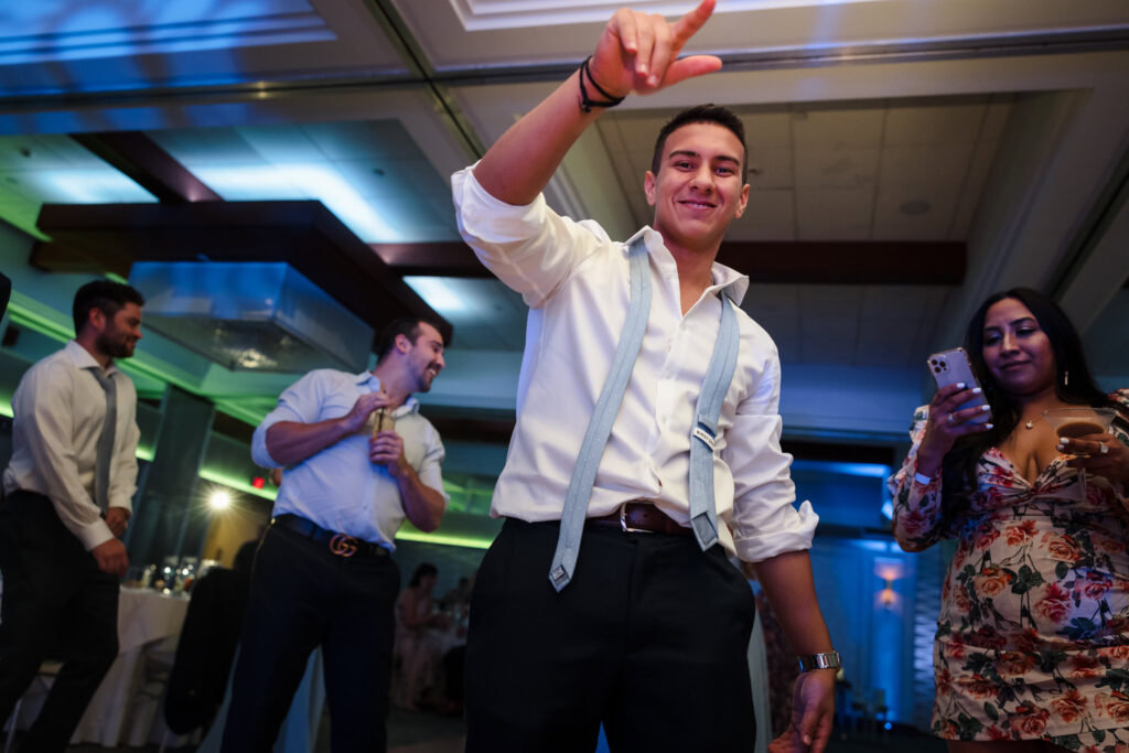 Wedding guest dances on the floor during the reception at a Crescent Beach Club waterfront wedding, with guests celebrating under colorful uplighting late into the night.