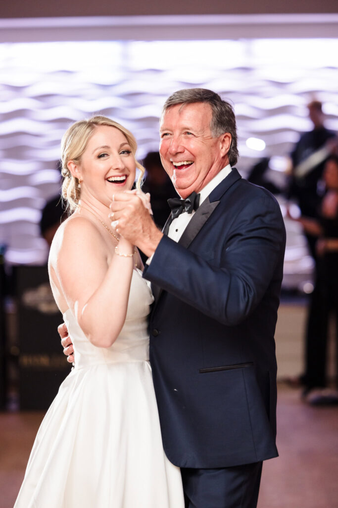 Bride and her father share a joyful, heartfelt dance, smiling and laughing together during the wedding reception.