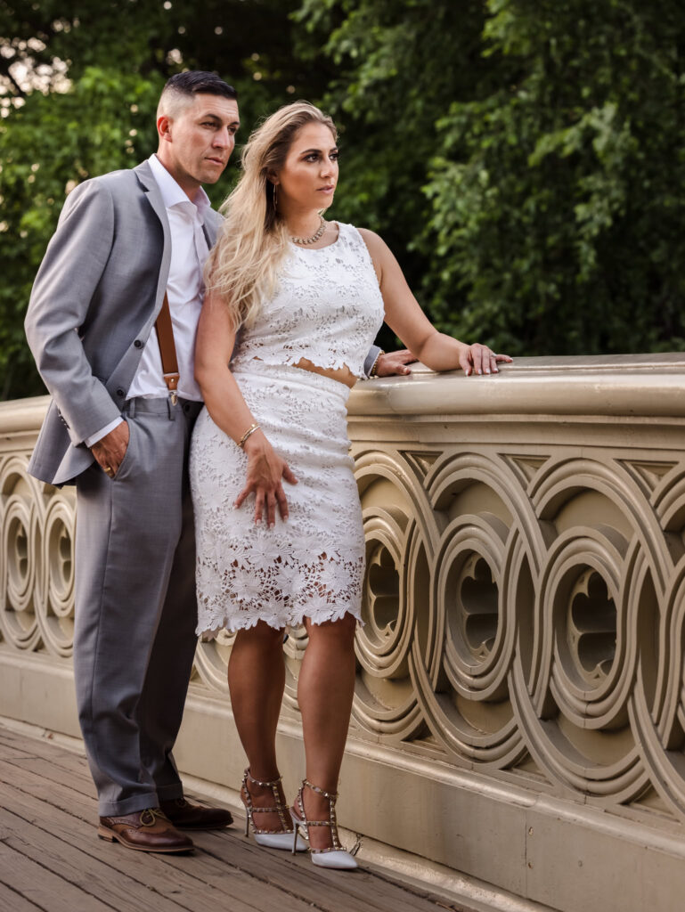 Stylish couple poses with serene confidence on Bow Bridge during their fashion-inspired engagement session in Central Park.