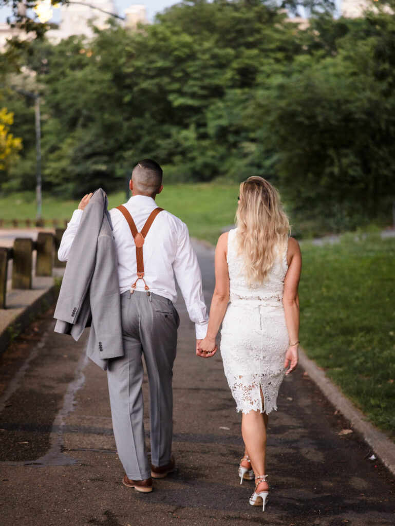 Engaged couple walking hand in hand through Central Park at dusk, capturing a timeless editorial moment with refined style and natural connection.
