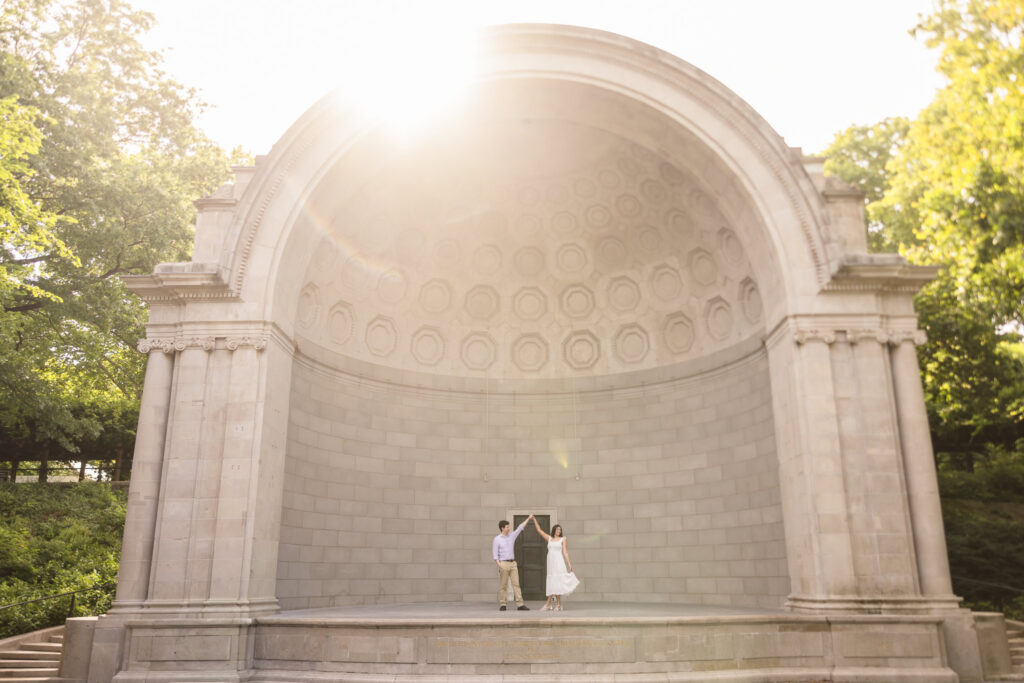 Couple dancing together in the warm evening light at the Naumburg Bandshell during their Central Park engagement session in New York City.