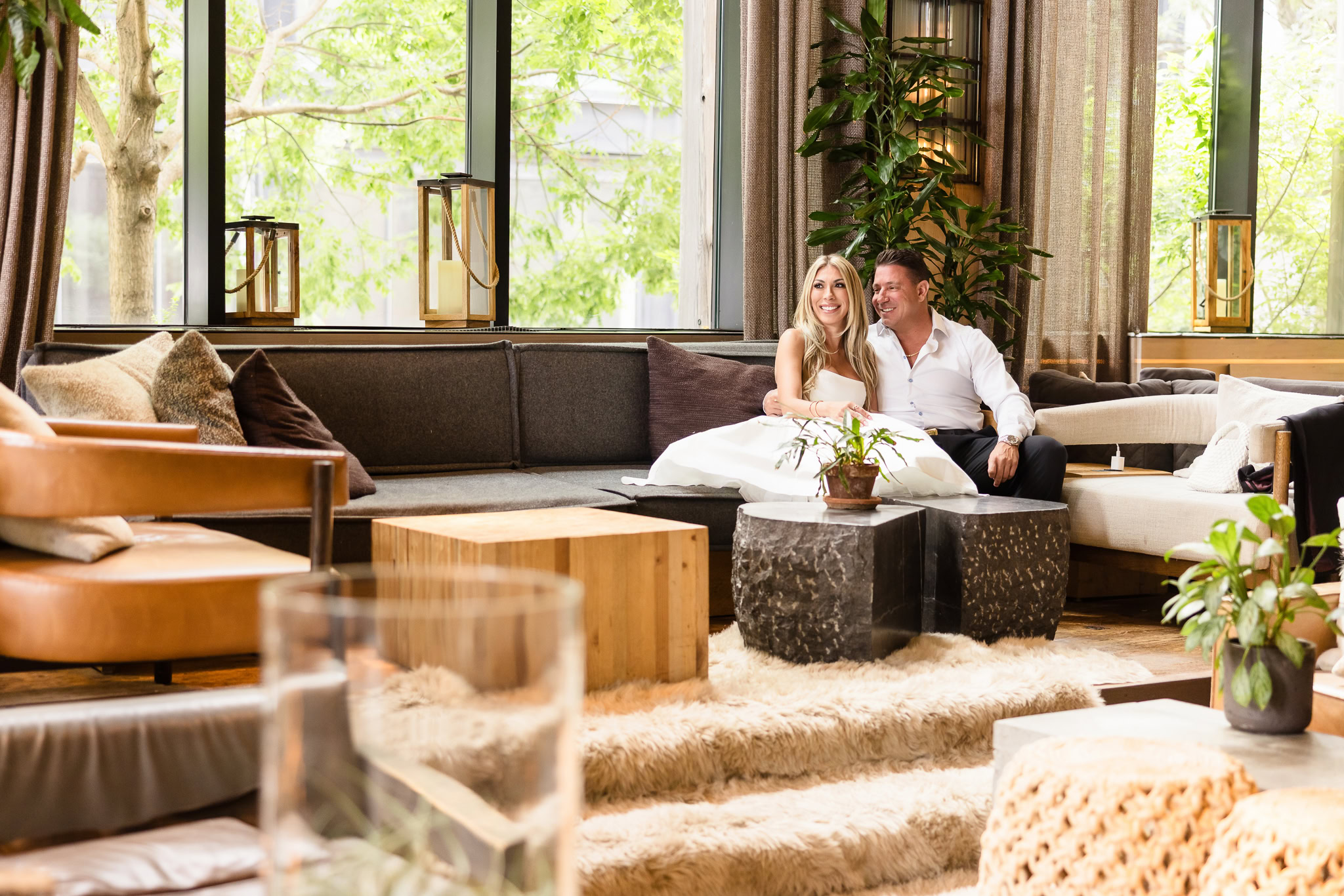 Couple relaxing together inside a modern DUMBO lounge during their DUMBO engagement session, capturing intimate engagement photos in DUMBO Brooklyn with natural window light and refined urban styling.