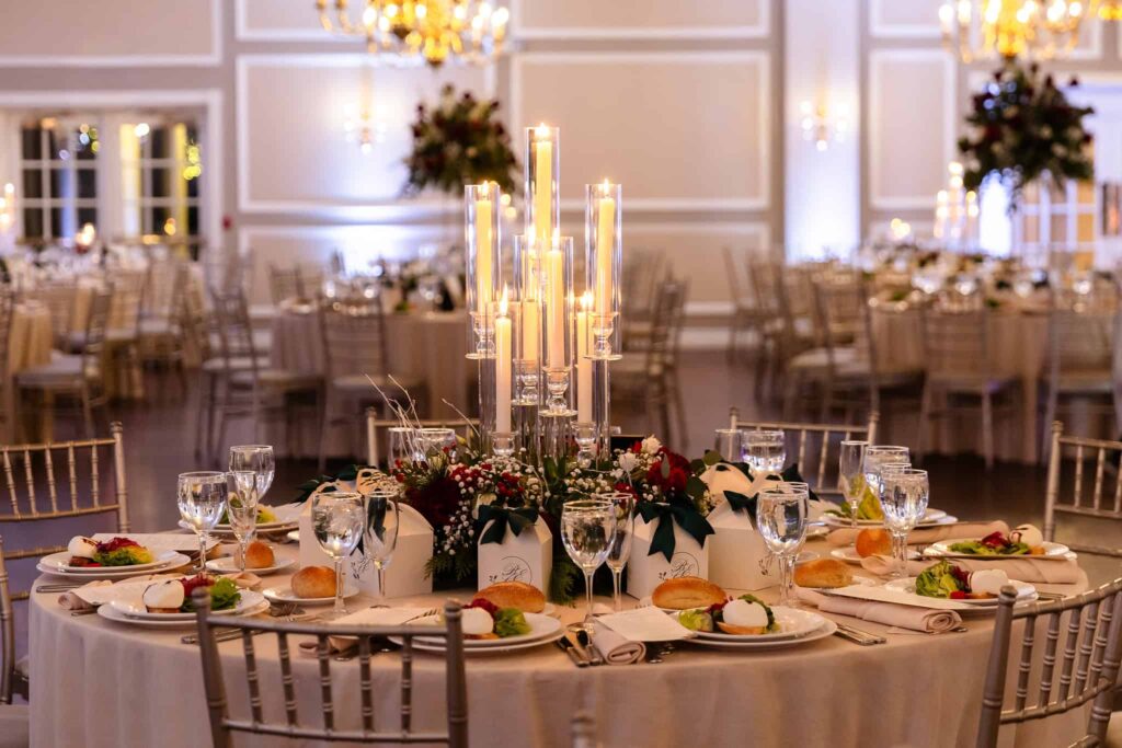 Candlelit reception table at an Estate at East Wind wedding, featuring elegant place settings, tall glass candle centerpieces, and a refined indoor reception space on Long Island.