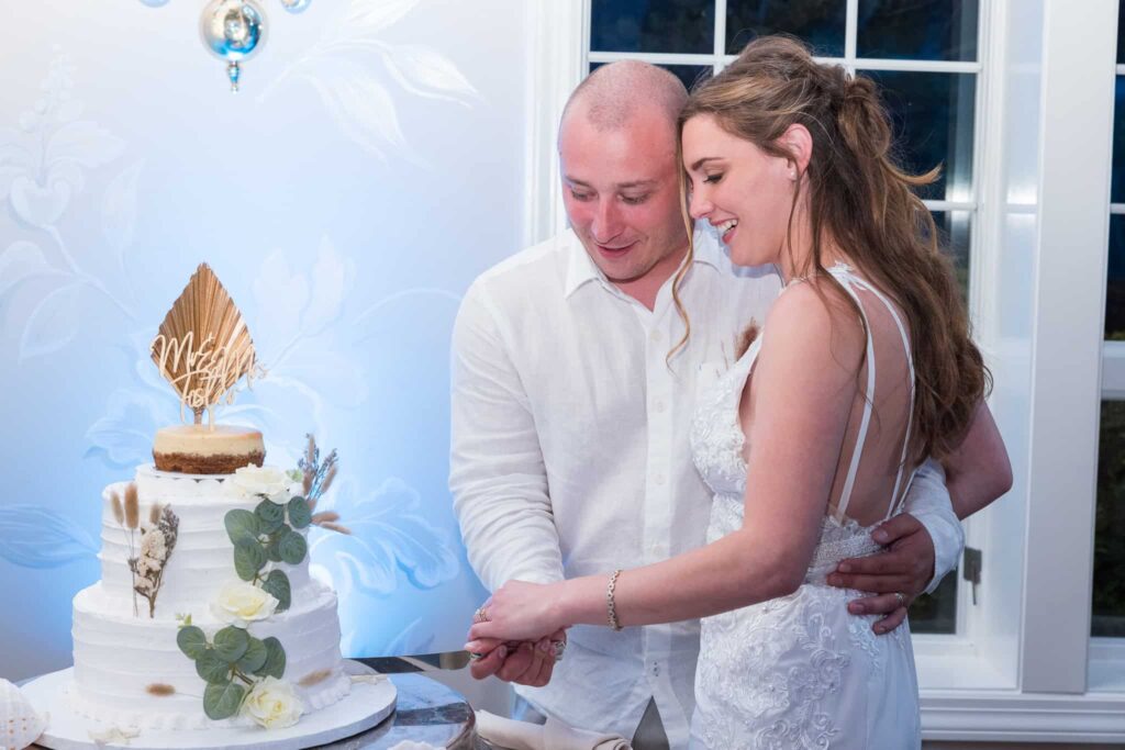 Bride and groom cutting their wedding cake during an Estate at wedding reception, sharing a quiet, joyful moment inside the elegant Long Island venue.