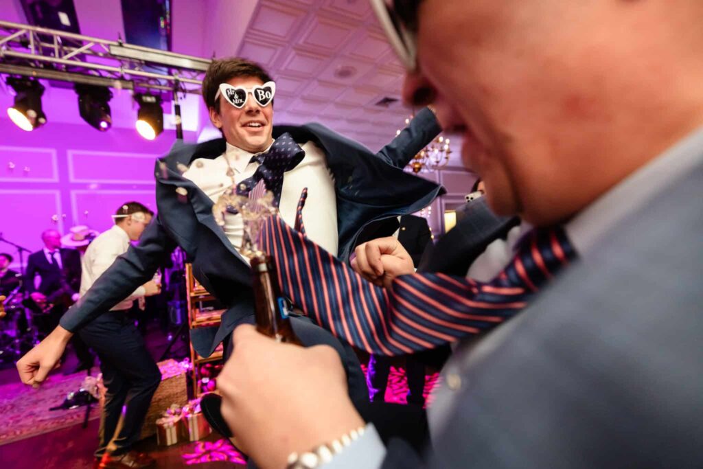 High-energy dance floor moment during an Estate at East Wind wedding reception, capturing guests celebrating under colorful lighting inside the classic Long Island ballroom.