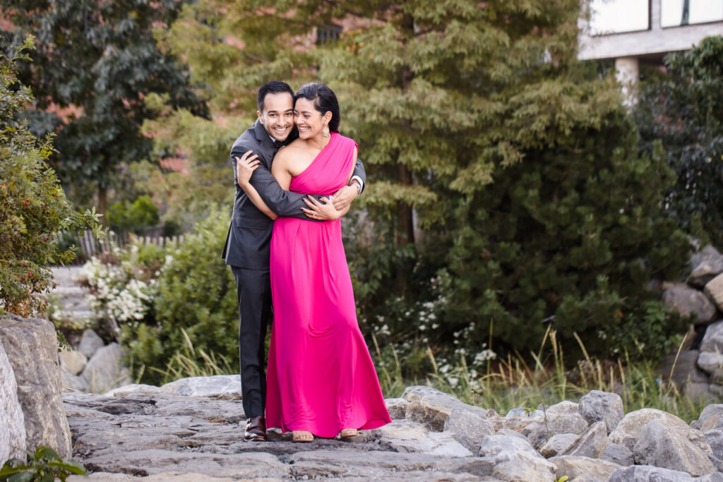 Brooklyn waterfront engagement session portrait of Mahati and Winston embracing in formal attire, highlighting a sari inspired engagement dress.