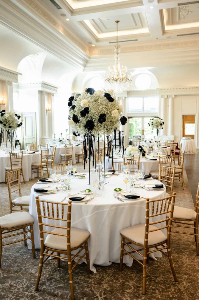 Elegant reception tables with tall black and white floral centerpieces beneath crystal chandeliers at a Park Chateau Estate and Gardens wedding in East Brunswick, New Jersey.