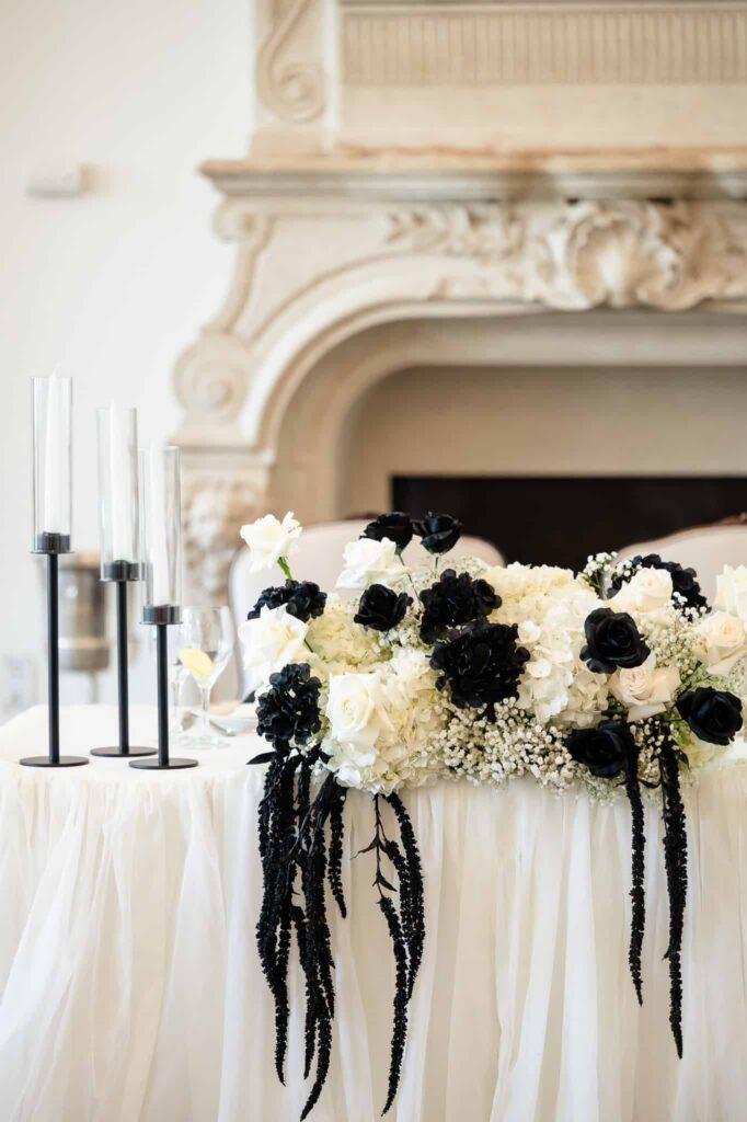 Black and white sweetheart table florals in front of the ornate fireplace at a Park Chateau Estate and Gardens wedding, highlighting this refined NJ estate wedding venue.