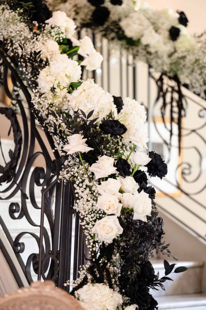 Close-up of black and white floral garland cascading along the grand staircase at Estate and Gardens, an elegant NJ estate wedding venue in East Brunswick.