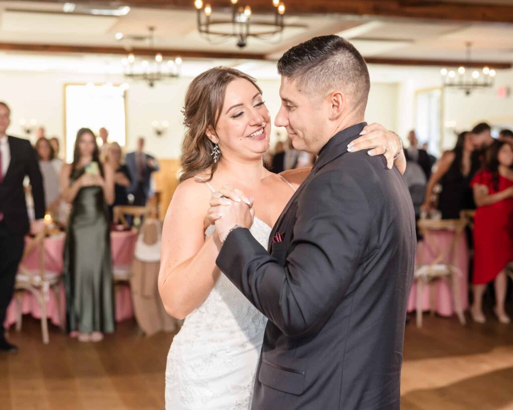Bride and groom sharing their first dance during a Vineyard at East Wind wedding reception, surrounded by guests and rustic elegant decor.