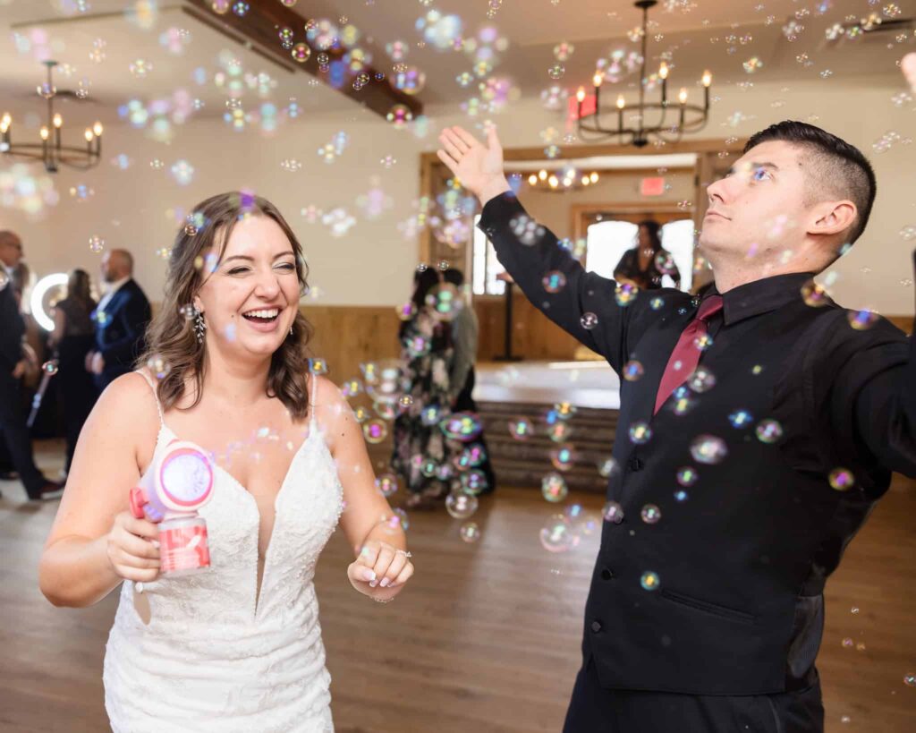 Bride and groom laughing and playing with bubbles on the dance floor during their fun-filled Vineyard at East Wind wedding reception.