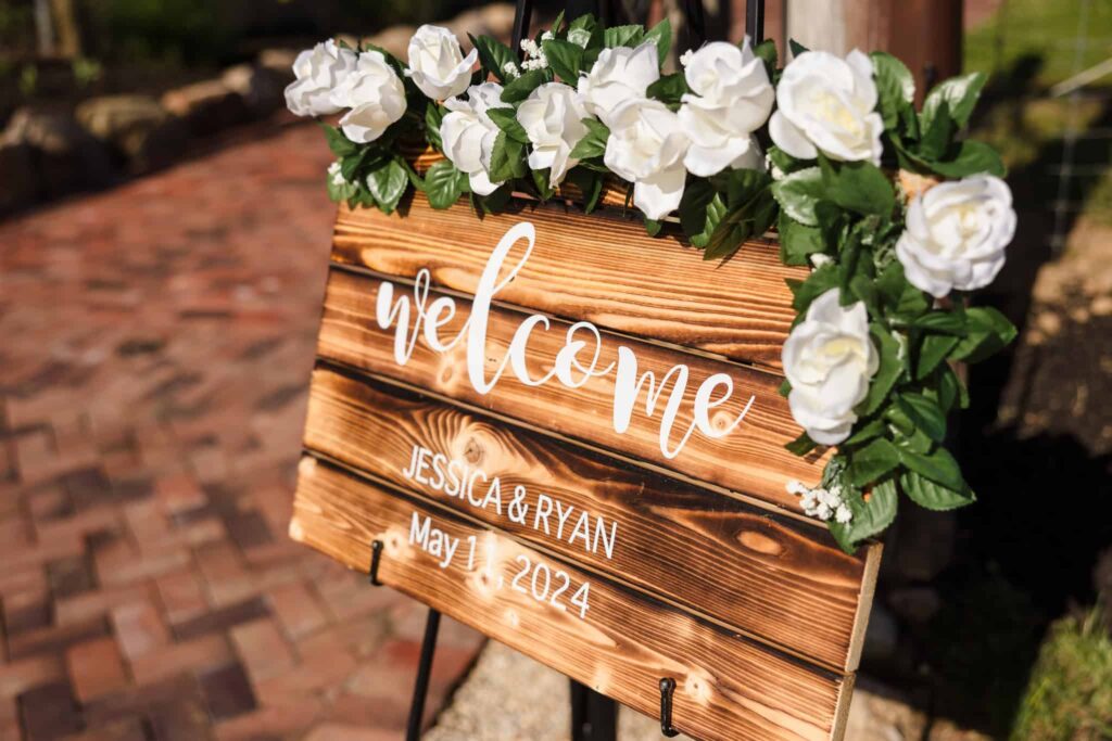 Bride and groom standing on a wooden bridge near a fountain, surrounded by ornamental grasses at the Vineyard at East Wind.