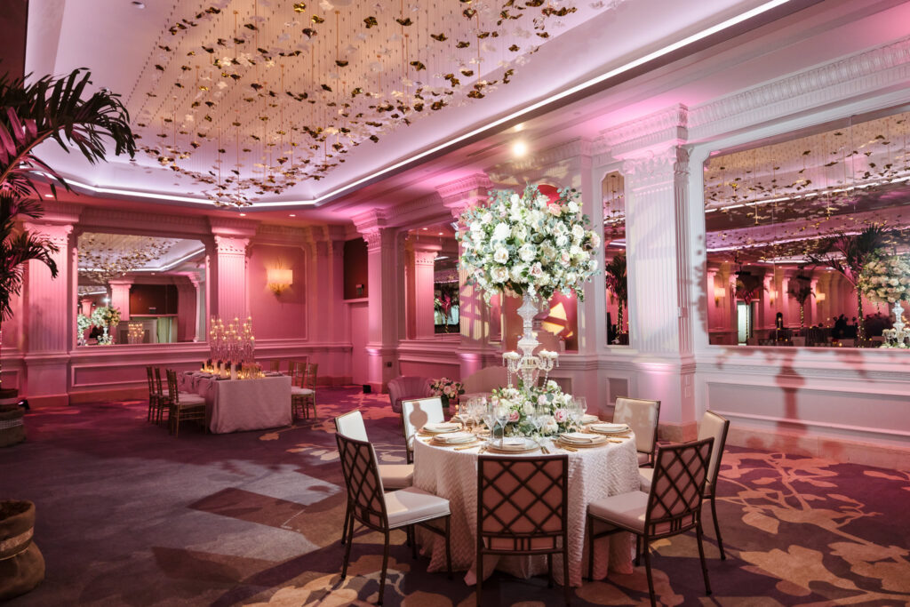 Elegant reception table with tall floral centerpiece and blush lighting inside the renovated Garden City Hotel ballroom during the Blush Hour wedding showcase.