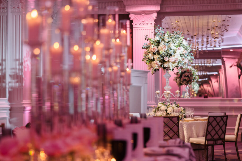 Tall floral centerpiece and glowing candle display reflecting in mirrors inside the Garden City Hotel ballroom during the Blush Hour wedding showcase.