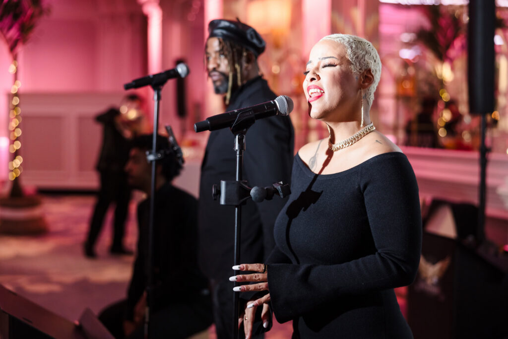 Live vocalist performing with a band during the Blush Hour showcase inside the Garden City Hotel ballroom, highlighting entertainment for luxury Long Island weddings.