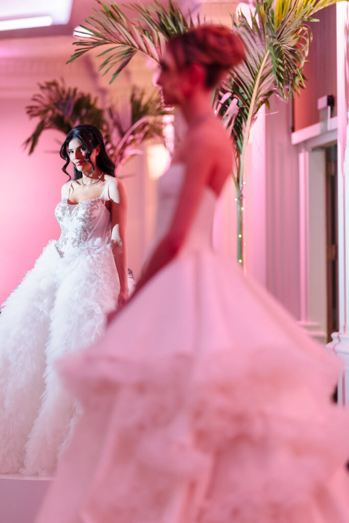 Bridal models in couture wedding gowns displayed under blush lighting inside the ballroom during the Blush Hour wedding showcase in NY.