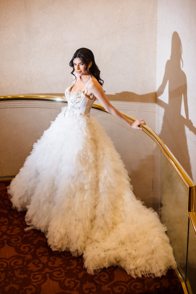 Bridal model in a dramatic ruffled ball gown posing on the staircase during the Blush Hour wedding showcase in Garden City, NY.