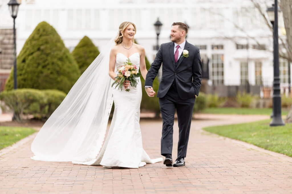 Classic wedding portrait by a Luxury Wedding Photographer Long Island of a couple walking along a brick path outside an elegant estate