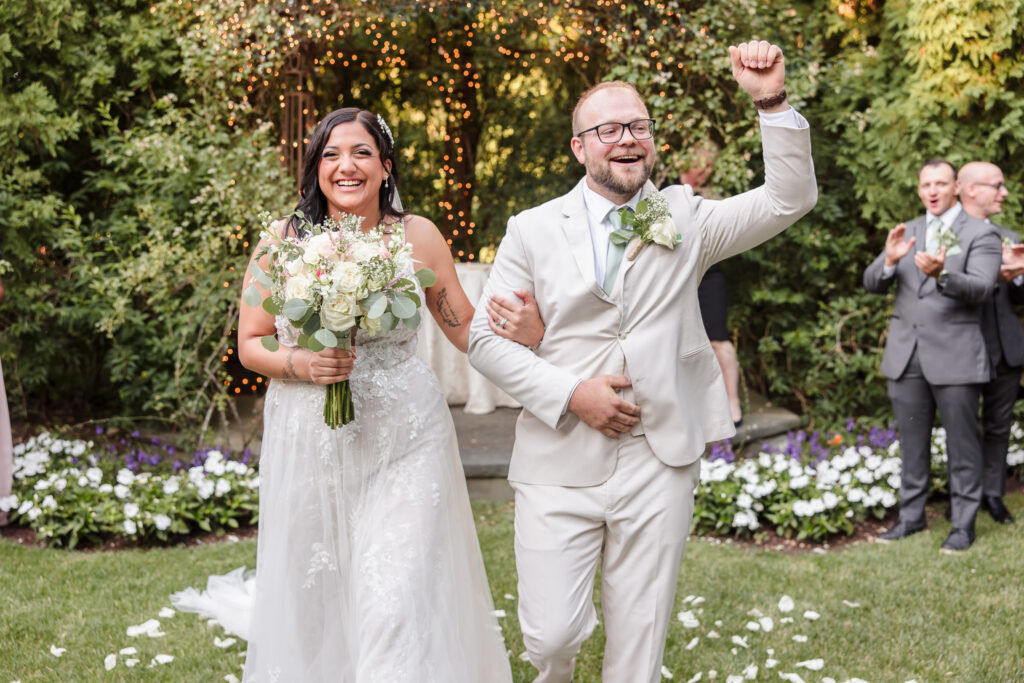 Wedding ceremony recessional as newlyweds celebrate with guests in a garden setting