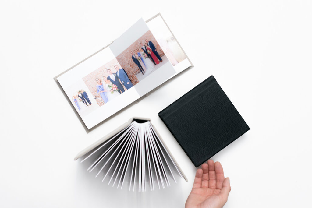Luxury wedding album and printed photographs displayed on a clean white background before delivery to a couple.