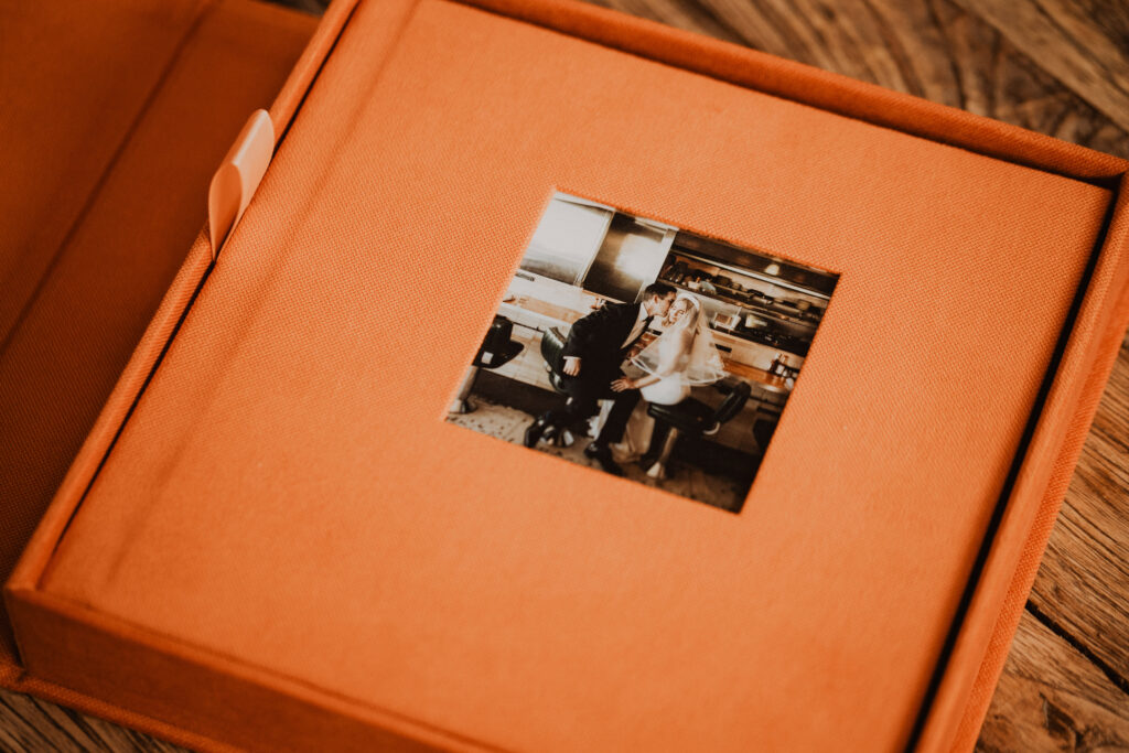 Luxury linen wedding album photographed on a wooden table showcasing a printed heirloom wedding experience.