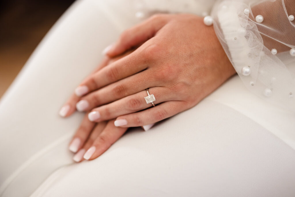 Close-up photograph of a bride’s engagement ring resting on her hands during the wedding day.