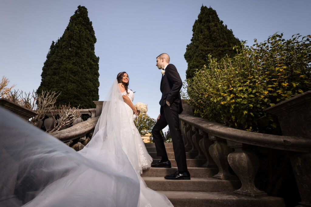 Bride and groom standing on the stone staircase at Old Westbury Gardens during an elegant Long Island wedding.