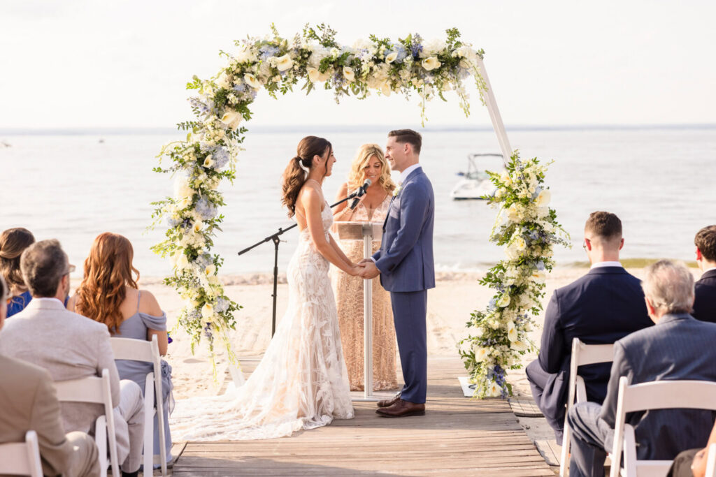 Oceanfront wedding ceremony at Crescent Beach Club on Long Island with floral arch overlooking the water.