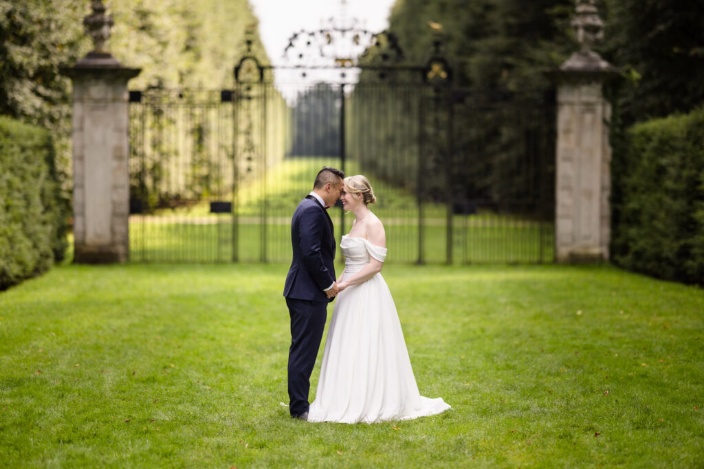 Bride and groom holding hands in front of an elegant garden estate during a Long Island wedding portrait session