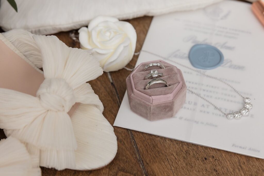 Refined wedding detail photograph featuring bridal shoes, rings, invitation suite, and jewelry