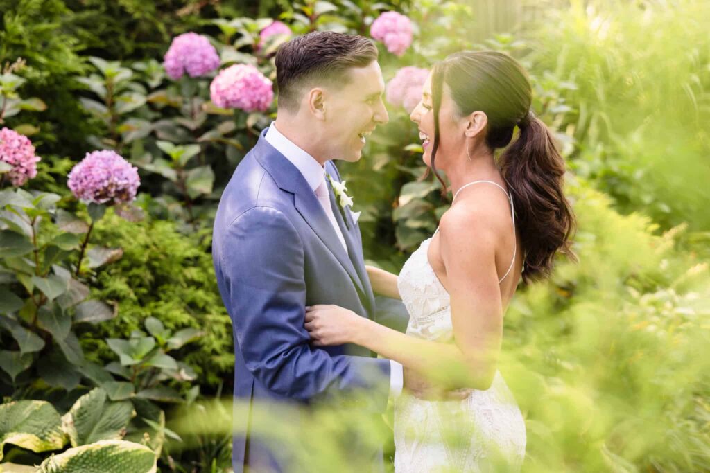 Joyful couple laughing together in a garden portrait captured by an experienced wedding photographer on Long Island.