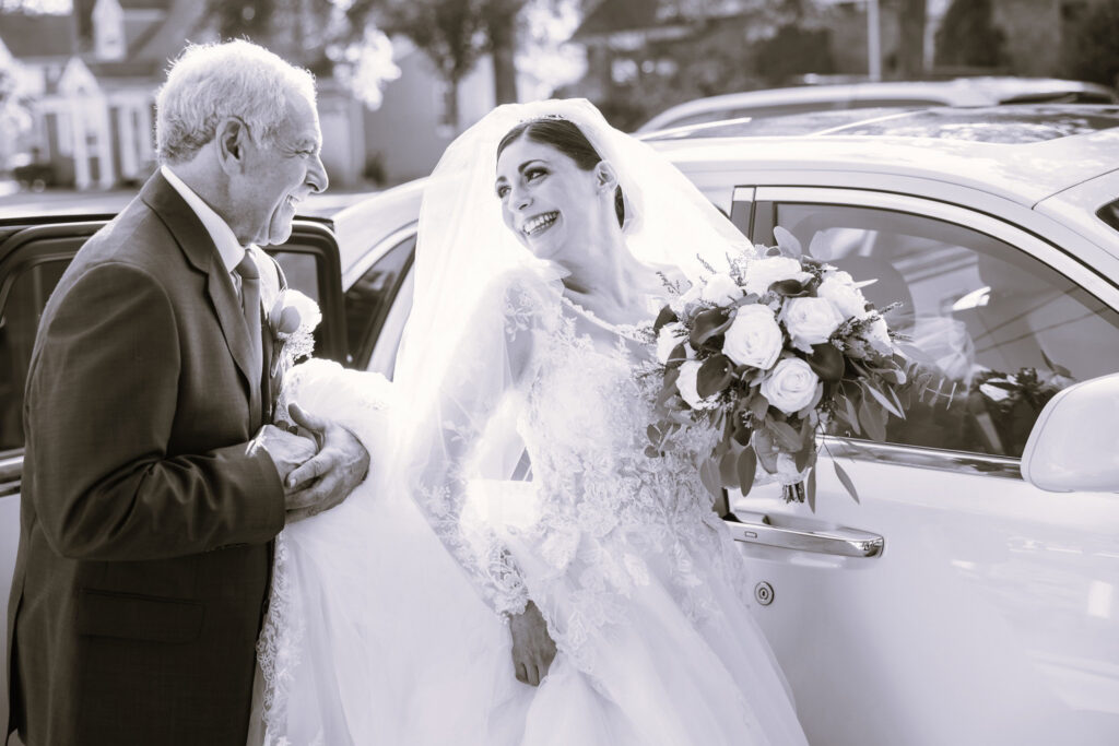 Emotional black and white portrait of a bride sharing a joyful moment with her father before the ceremony